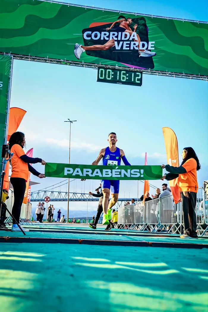 Izaias Vidal rompendo a faixa de chegada da Corrida Verde, com a ponte Hercílio Luz ao fundo